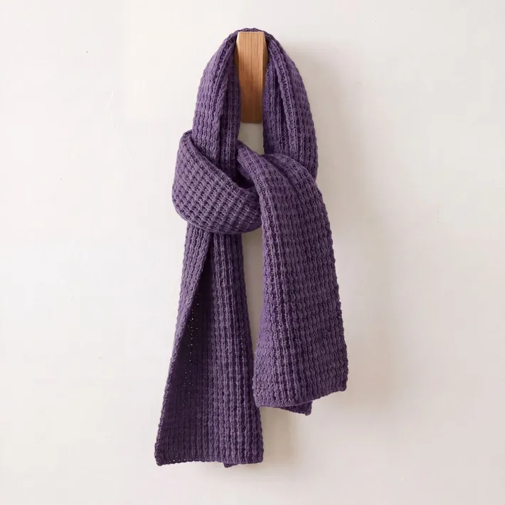 Purple waffle knit baby alpaca scarf displayed on a wooden wall hook