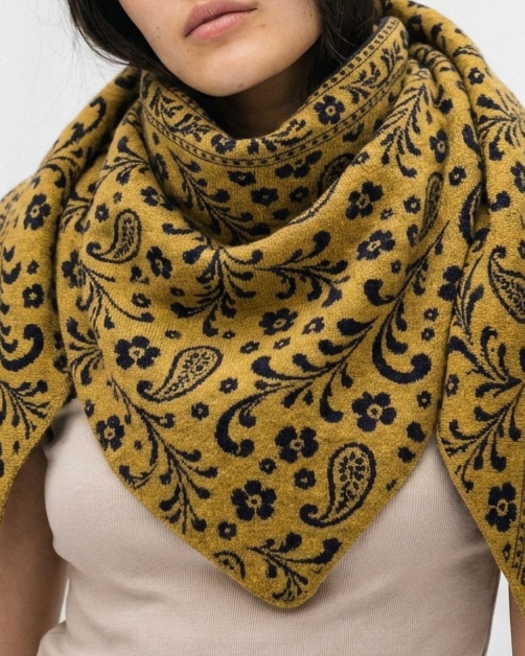 Model wearing the navy and mustard gold paisley alpaca triangle scarf indoors