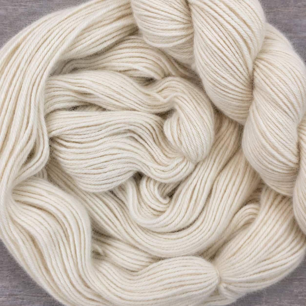 Single skein showing the soft halo and four-ply structure of natural white baby alpaca yarn